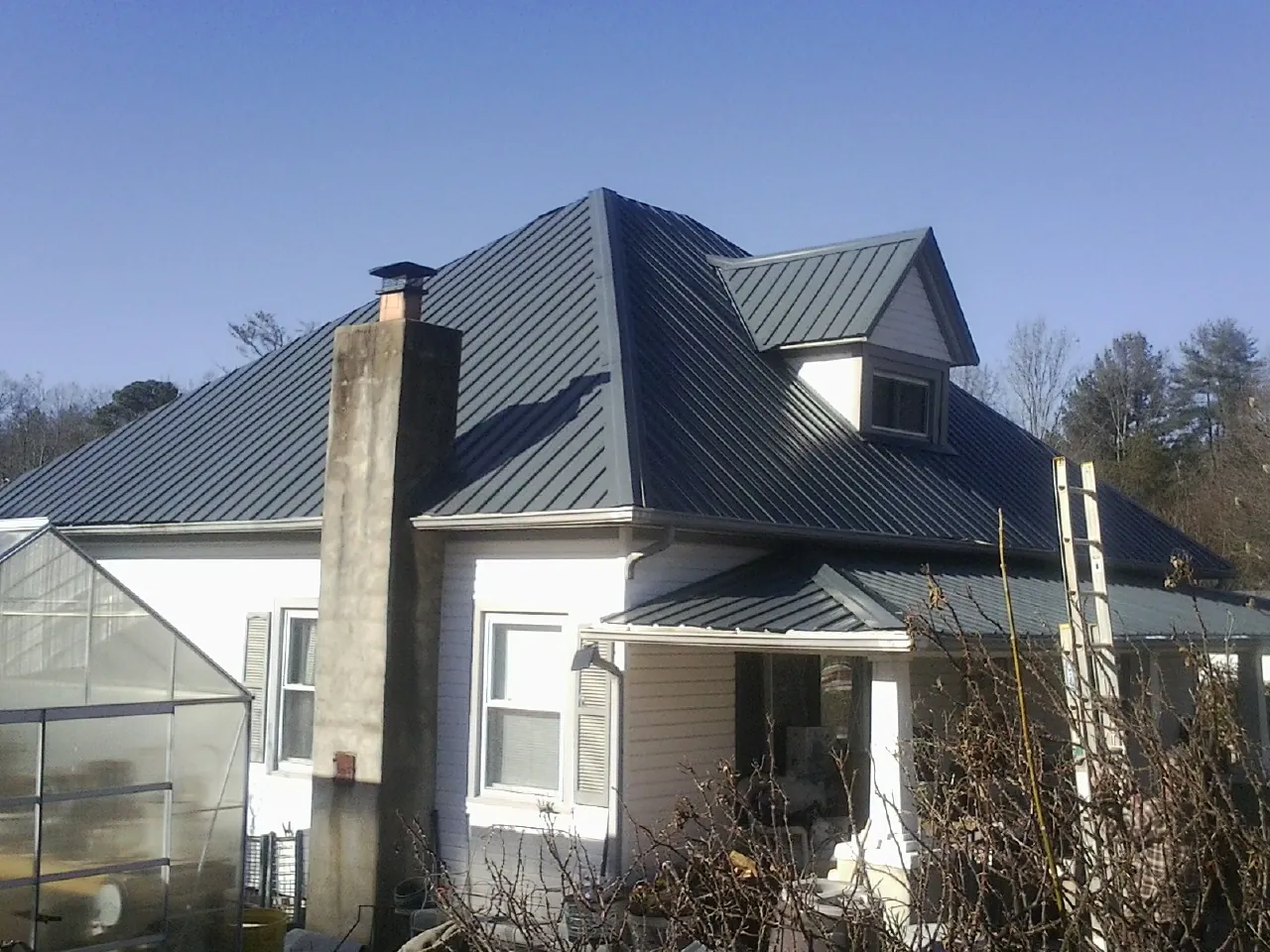 Dark blue standing seam metal roof on a white farmhouse with dormer — Slate & Tile Roof Repair by Roofing Brothers in Lithia