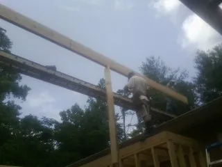 Carpenter setting a ridge beam over a new addition frame — Ice Dam Removal by Roofing Brothers in Lithia