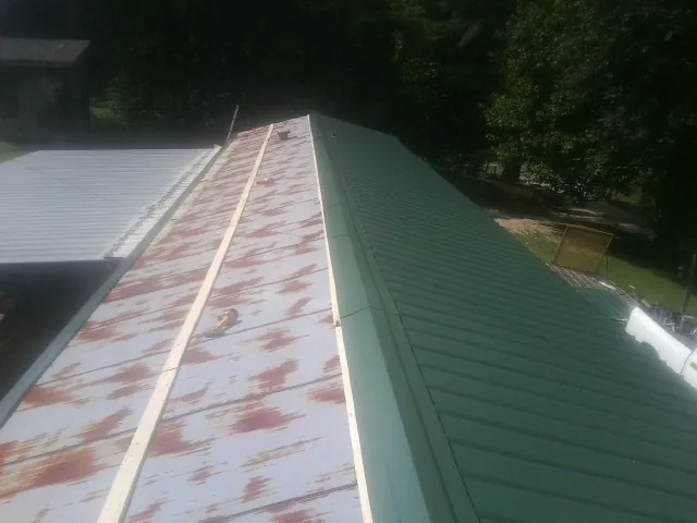 Old rusted panels beside newly installed green metal roofing — Wind Damage Roof Repair by Roofing Brothers in Lithia