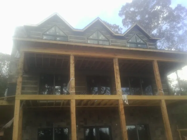 Dormers and porch framing on a large log home under construction — Roof Coating work by our crew in Lithia