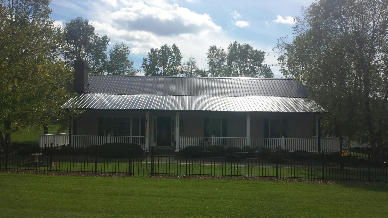 Gray metal roof on a brick ranch with a full width front porch — Gutter Guard Installation work by our crew in Lithia
