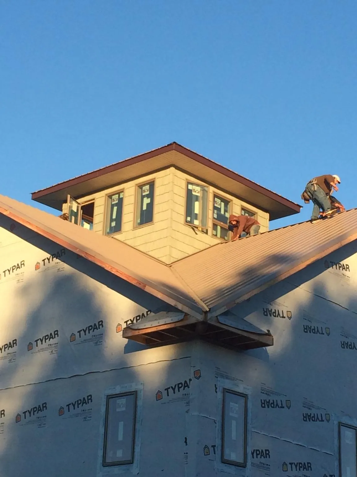 Roofers working around a rooftop cupola on a new metal roof at sunset — Roof Waterproofing in Lithia by Roofing Brothers